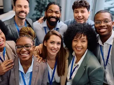 Diverse smiling sales team wearing conference badges in a modern office, illustrating customer relationship management with Slaeb CRM